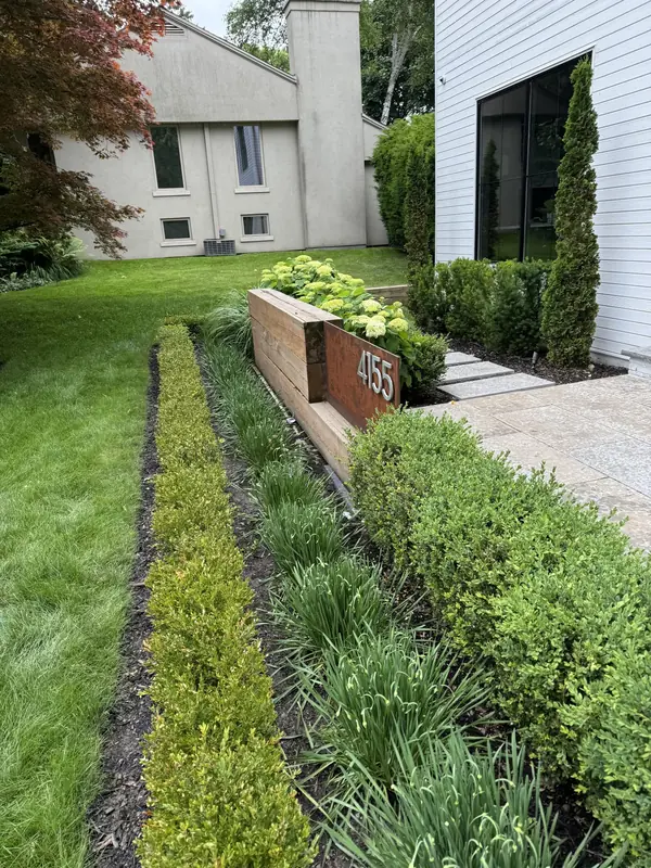 Front yard garden with a boxwood hedge, ornamental grasses and a steel address planter
